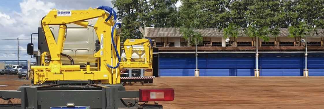 Guindaste veicular articulado instalado em caminhão, mostrando estrutura montada no chassi para operações de movimentação de carga.