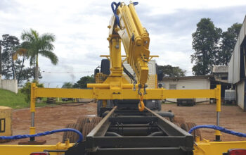 Guindaste veicular com patolas totalmente abertas e apoiadas no solo, demonstrando o patolamento correto para ampliar a base de sustentação e garantir estabilidade durante a operação de içamento.